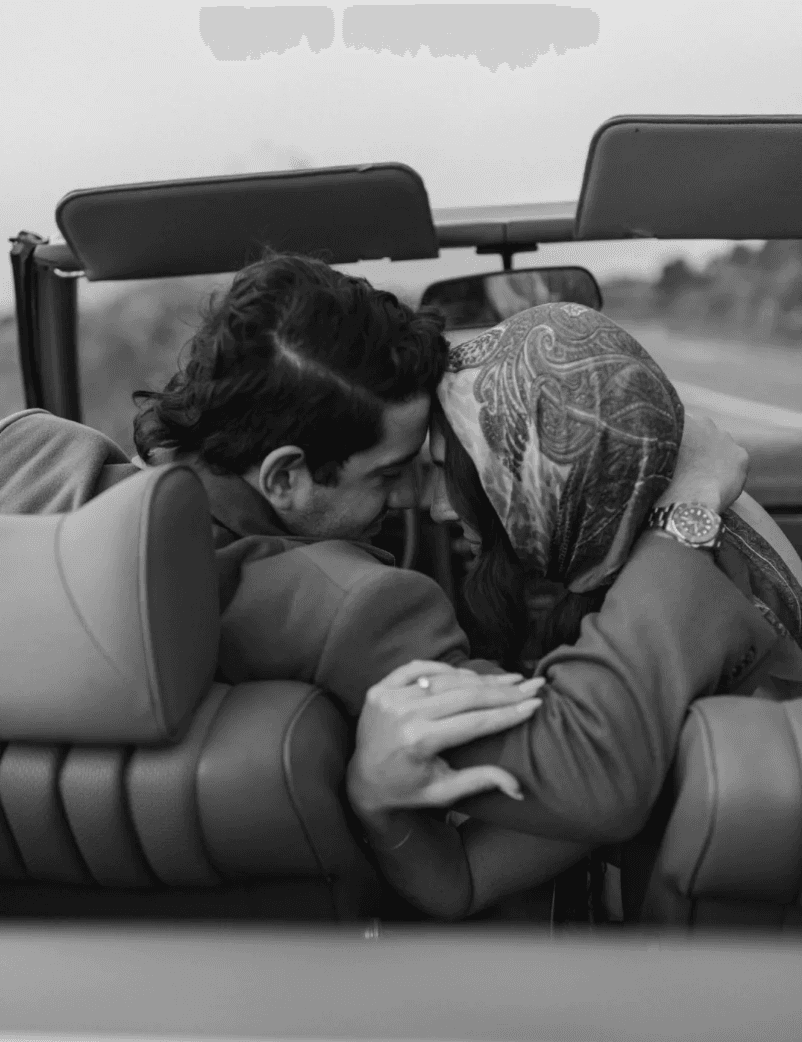 Un couple enlacé, front contre front, à l'arrière d'une voiture décapotable.