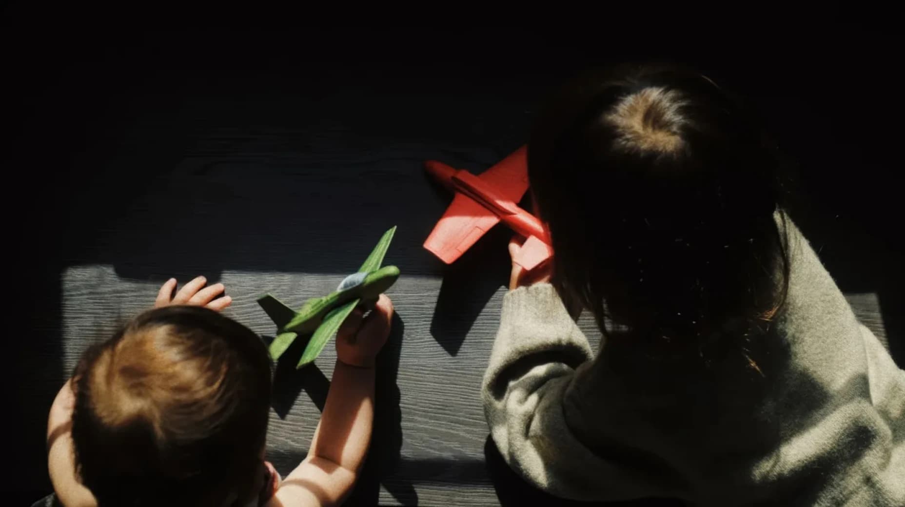 Deux jeunes enfants jouent avec des avions miniatures au soleil.