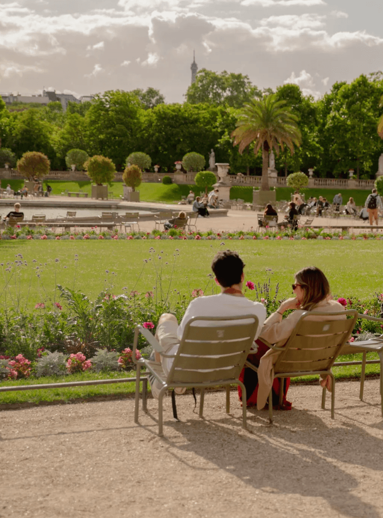 Un couple assis dans un parc, une tour Eiffel visible au loin.